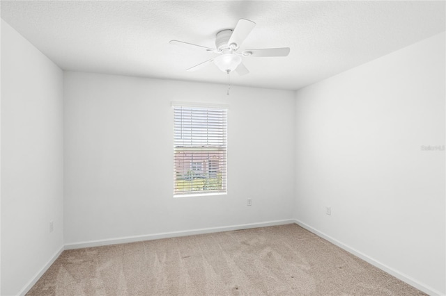 carpeted spare room featuring baseboards, a textured ceiling, and ceiling fan