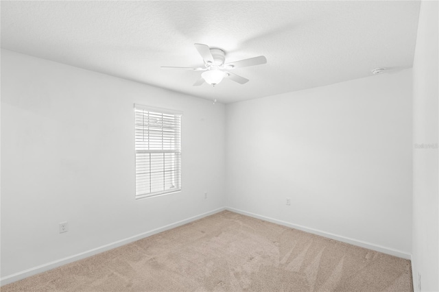 empty room with carpet floors, ceiling fan, baseboards, and a textured ceiling