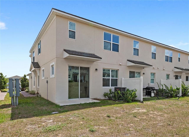 rear view of house featuring a yard and stucco siding