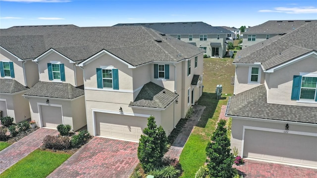 view of front of home with a residential view, stucco siding, decorative driveway, and an attached garage