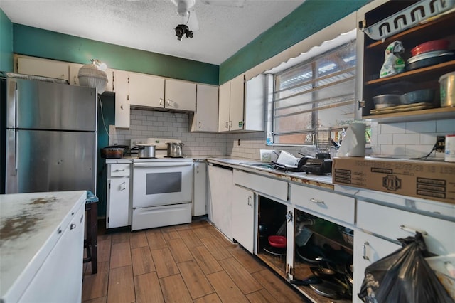 1136 Lakewood Park Dr, Daytona Beach, FL 32117 - kitchen with tasteful backsplash, light countertops, freestanding refrigerator, white cabinetry, and white range with electric stovetop