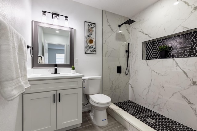 bathroom with vanity, a marble finish shower, and toilet