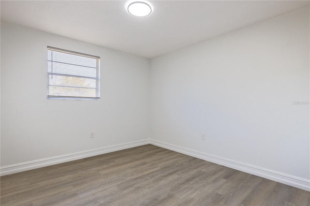 spare room featuring baseboards and wood finished floors