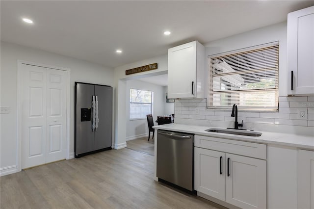 kitchen featuring backsplash, appliances with stainless steel finishes, white cabinetry, and a sink