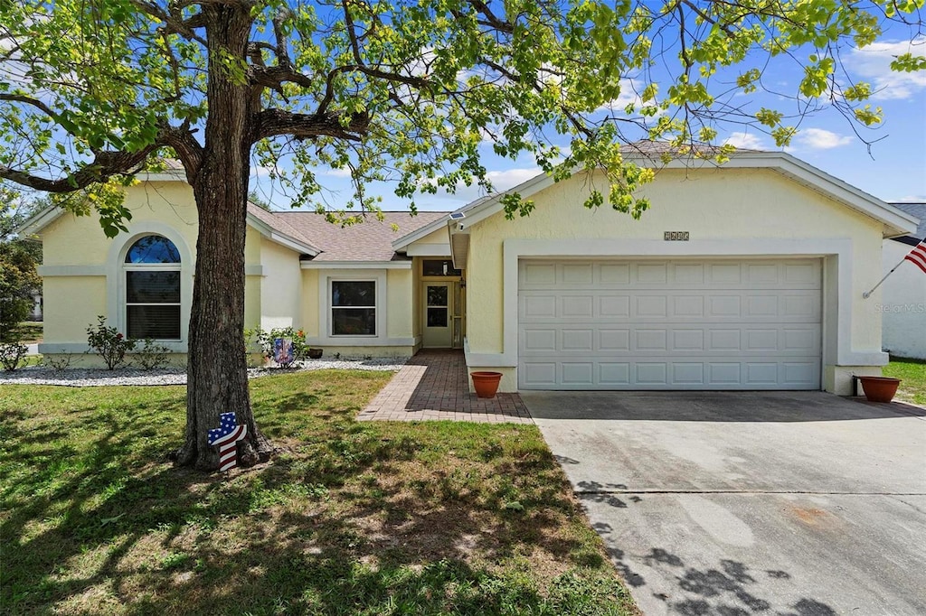ranch-style home with a front lawn, stucco siding, driveway, roof with shingles, and a garage
