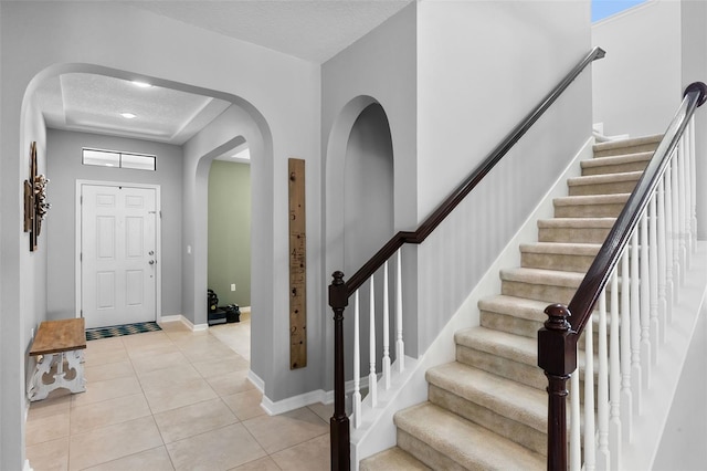 4113 Longbow Dr, Clermont, FL 34711 - foyer with arched walkways, light tile patterned flooring, stairs, baseboards, and a textured ceiling
