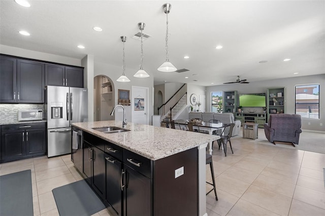 4113 Longbow Dr, Clermont, FL 34711 - kitchen featuring a sink, stainless steel refrigerator with ice dispenser, white microwave, arched walkways, and a kitchen bar