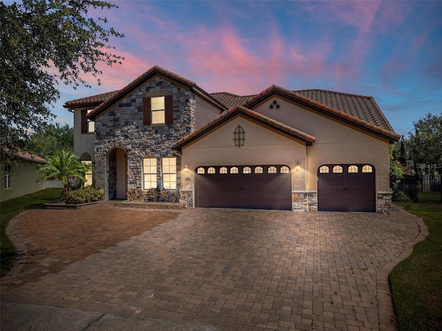 8625 Brixford St, Orlando, FL 32836 - view of front of home featuring stucco siding, stone siding, decorative driveway, a tile roof, and a garage