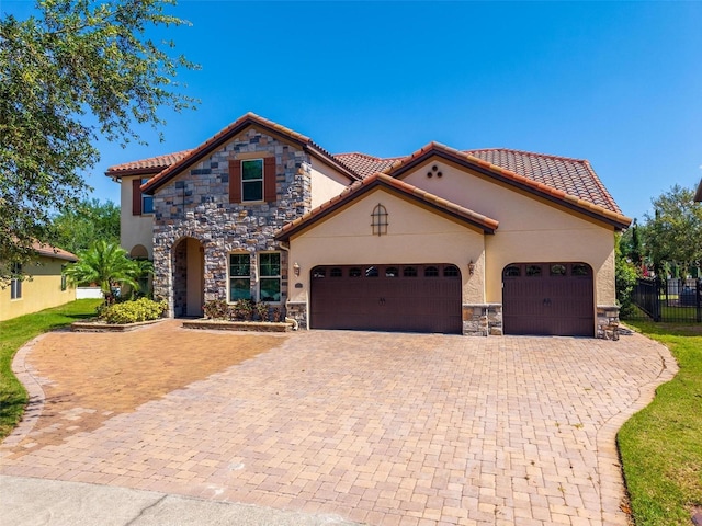 8625 Brixford St, Orlando, FL 32836 - mediterranean / spanish home with a tiled roof, stone siding, a garage, fence, and decorative driveway