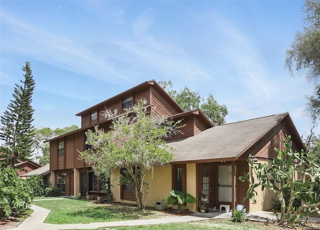 view of front of house featuring stucco siding, a front yard, and a balcony