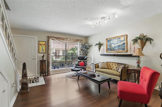 living area with baseboards, stairway, wood finished floors, and a textured ceiling