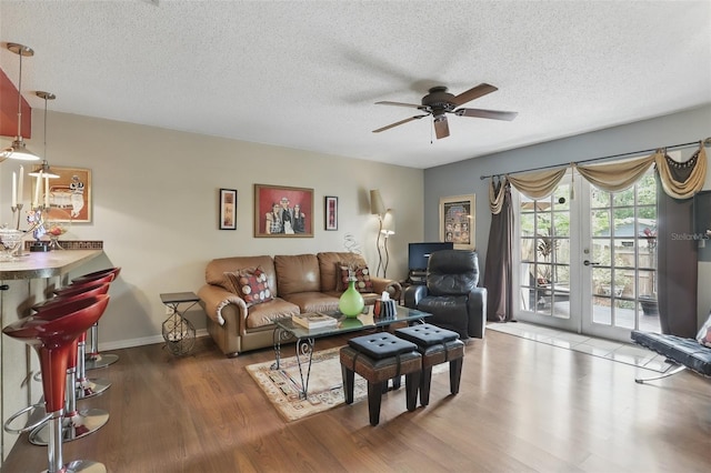 living area with ceiling fan, baseboards, wood finished floors, and a textured ceiling