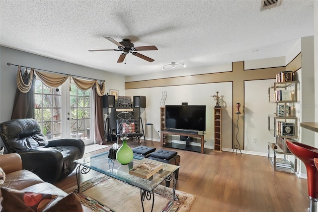 living area with visible vents, a ceiling fan, a textured ceiling, wood finished floors, and french doors