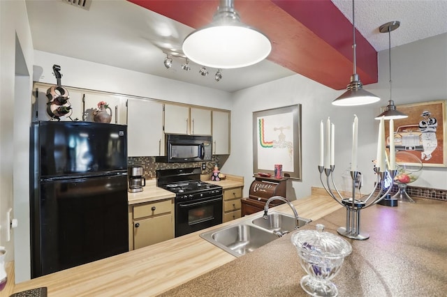 kitchen featuring pendant lighting, black appliances, light countertops, a sink, and backsplash