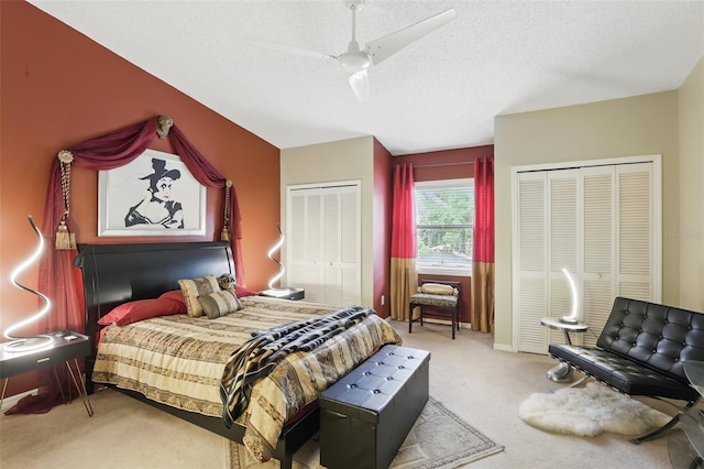 bedroom featuring multiple closets, ceiling fan, carpet, and a textured ceiling