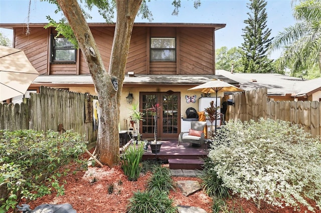 rear view of property with french doors and fence