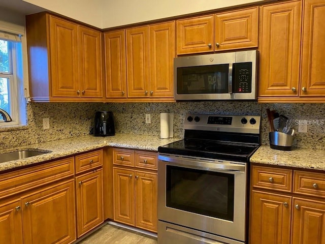19430 SW 100th Loop, Dunnellon, FL 34432 - kitchen featuring appliances with stainless steel finishes, a sink, decorative backsplash, and light stone countertops