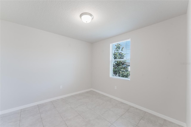 spare room featuring baseboards and a textured ceiling