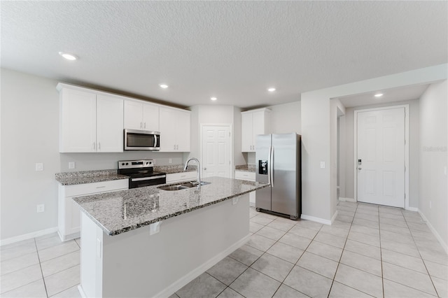 kitchen with recessed lighting, a textured ceiling, a kitchen island with sink, appliances with stainless steel finishes, and a sink