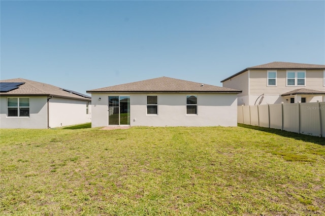 back of property featuring a yard, fence, and stucco siding