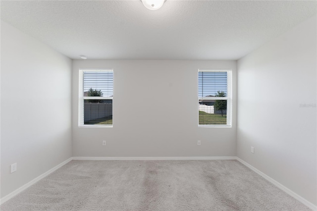 empty room with baseboards, light colored carpet, and a textured ceiling