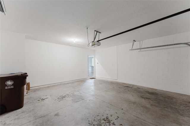 garage featuring a garage door opener and concrete block wall