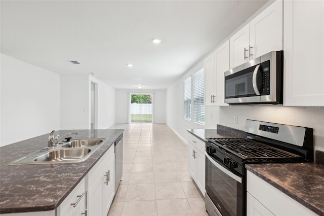 4717 Jasmine Cir, Leesburg, FL 34748 - kitchen with stainless steel appliances, a sink, light tile patterned floors, white cabinetry, and a kitchen island with sink