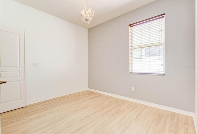 unfurnished room featuring baseboards, wood finished floors, and a notable chandelier