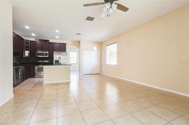 kitchen featuring tasteful backsplash, light tile patterned flooring, arched walkways, appliances with stainless steel finishes, and visible vents