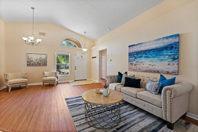 living area featuring vaulted ceiling, a notable chandelier, wood finished floors, and visible vents