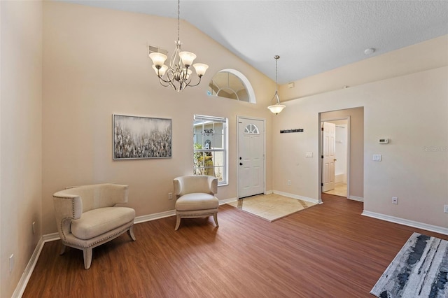 entrance foyer featuring vaulted ceiling, an inviting chandelier, wood finished floors, and visible vents