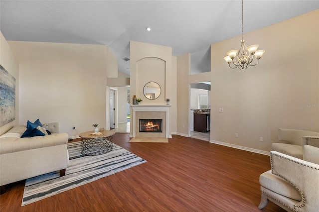 living area featuring an inviting chandelier, vaulted ceiling, wood finished floors, baseboards, and a fireplace