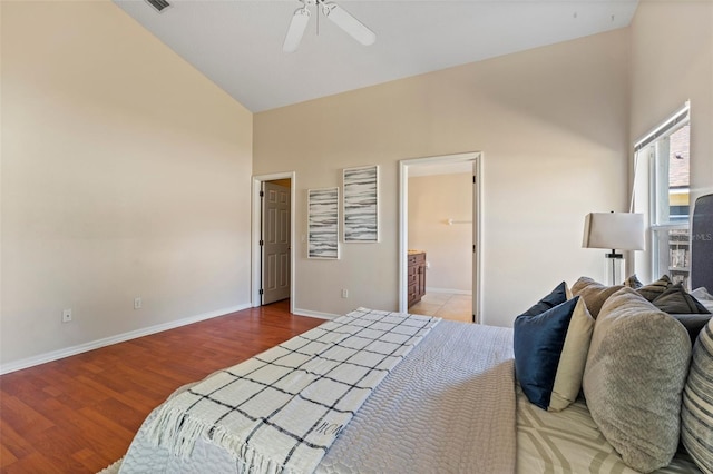bedroom with wood finished floors, baseboards, high vaulted ceiling, ceiling fan, and ensuite bathroom