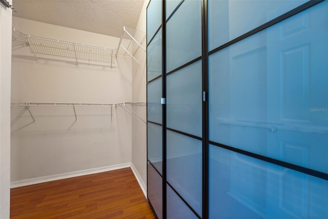 walk in closet with wood finished floors