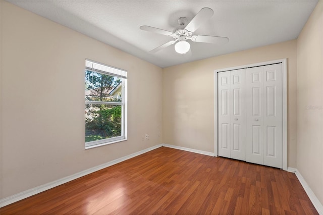 unfurnished bedroom with baseboards, a ceiling fan, wood finished floors, and a closet