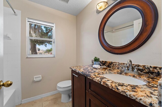 bathroom featuring a textured ceiling, vanity, baseboards, toilet, and tile patterned flooring