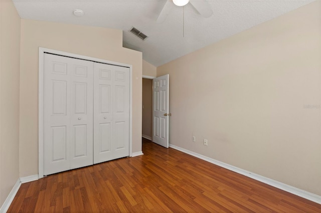 unfurnished bedroom featuring baseboards, wood finished floors, visible vents, and a closet