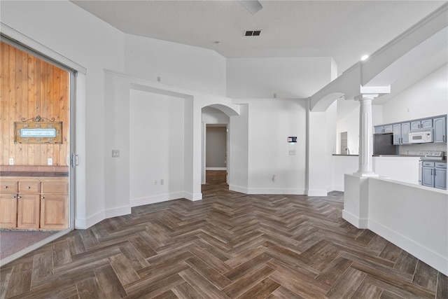 unfurnished living room featuring vaulted ceiling, visible vents, arched walkways, baseboards, and decorative columns