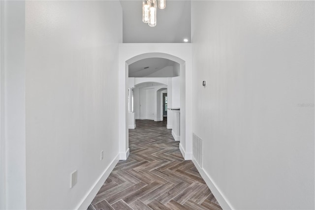 corridor featuring baseboards, visible vents, and arched walkways