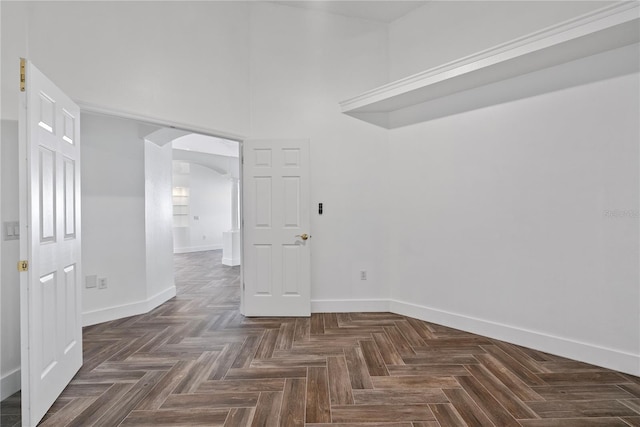 unfurnished room featuring arched walkways and baseboards