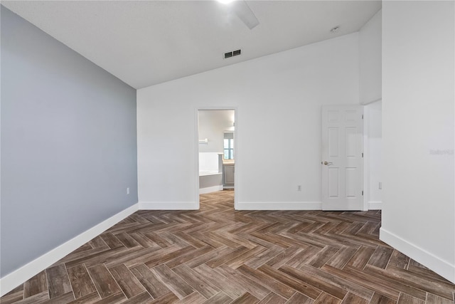 unfurnished room featuring baseboards, visible vents, and high vaulted ceiling