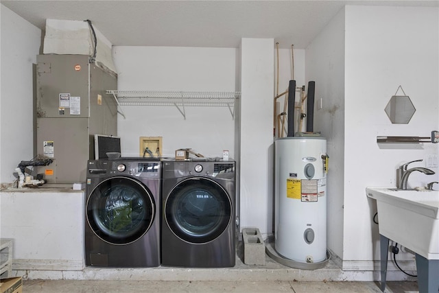 laundry area with heating unit, electric water heater, washer and dryer, and laundry area
