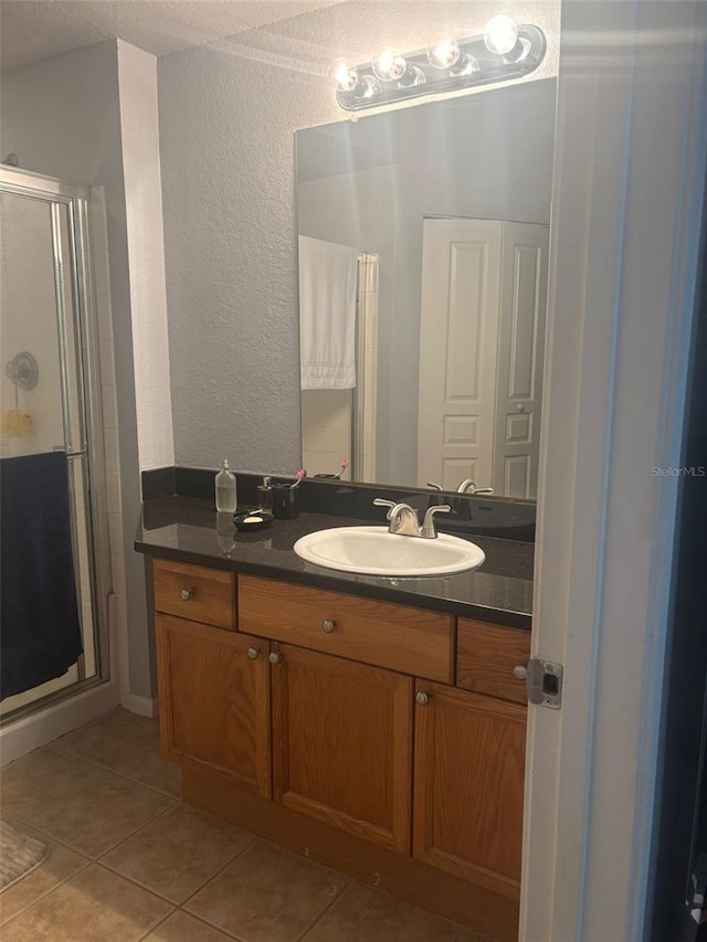 5125 Palm Springs Blvd Unit 13107, Tampa, FL 33647 - bathroom featuring tile patterned flooring, a stall shower, a textured wall, and vanity