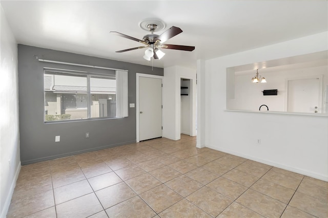 tiled spare room with baseboards and ceiling fan with notable chandelier