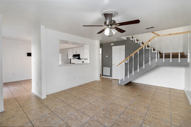 unfurnished living room with visible vents, tile patterned floors, a ceiling fan, and stairs