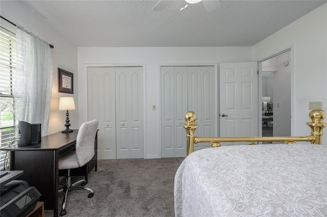 carpeted bedroom featuring multiple closets, a textured ceiling, and a ceiling fan