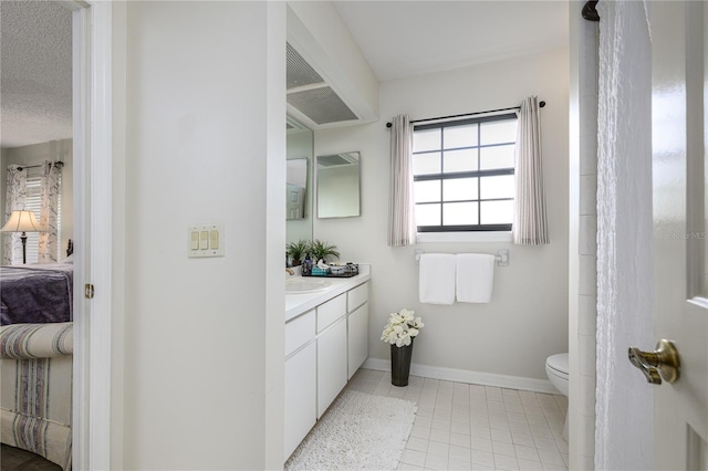ensuite bathroom with toilet, ensuite bathroom, baseboards, tile patterned flooring, and vanity