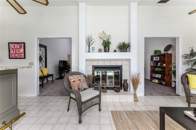 living area with a fireplace, visible vents, a ceiling fan, and light colored carpet