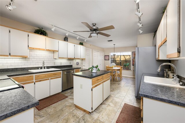 kitchen featuring dishwasher, rail lighting, a ceiling fan, and a sink
