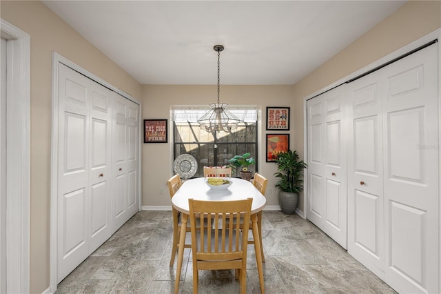 dining space featuring stone finish floor, baseboards, and an inviting chandelier